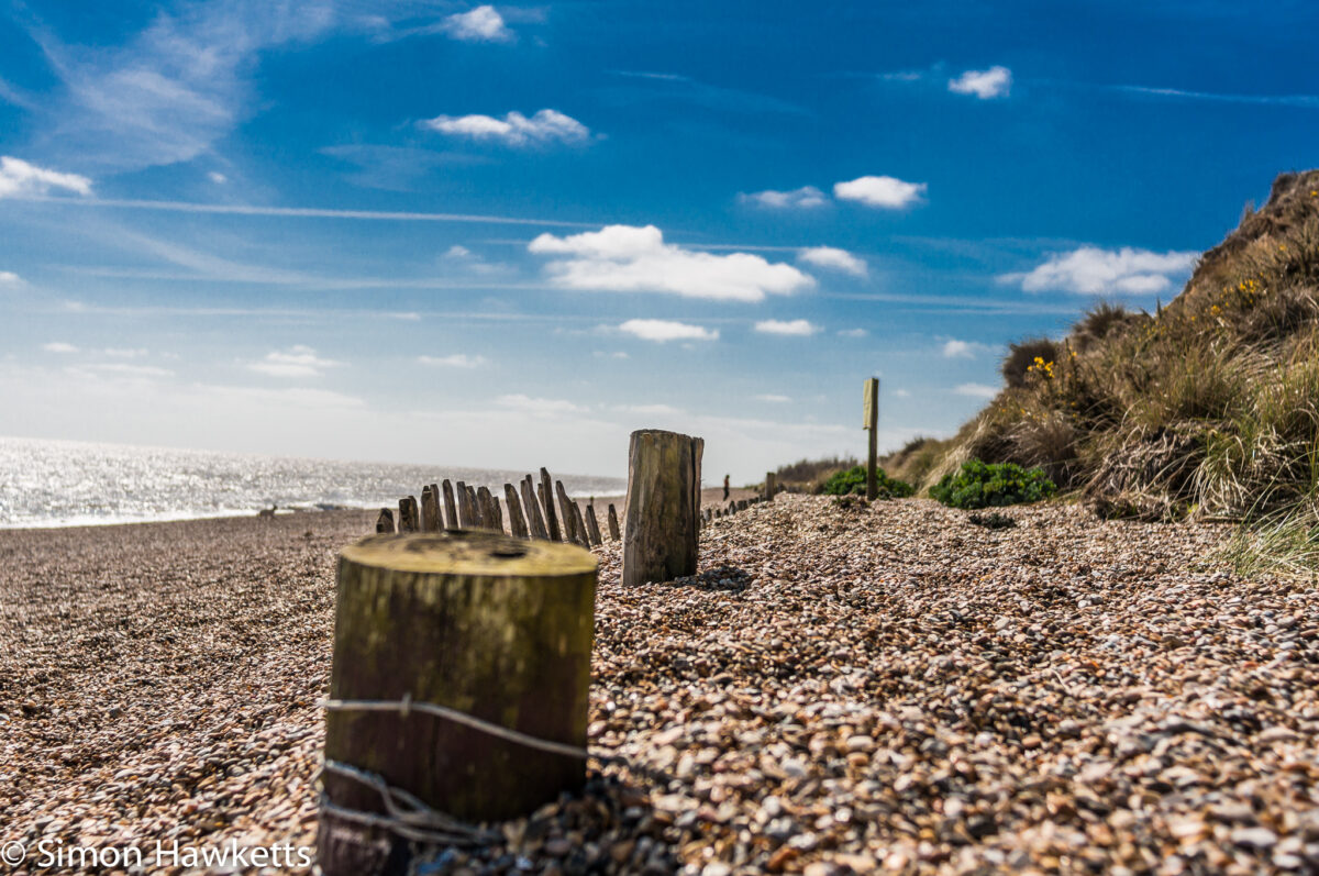 Dunwich Heath Suffolk pictures - A large fence post in the foreground with the beach behind