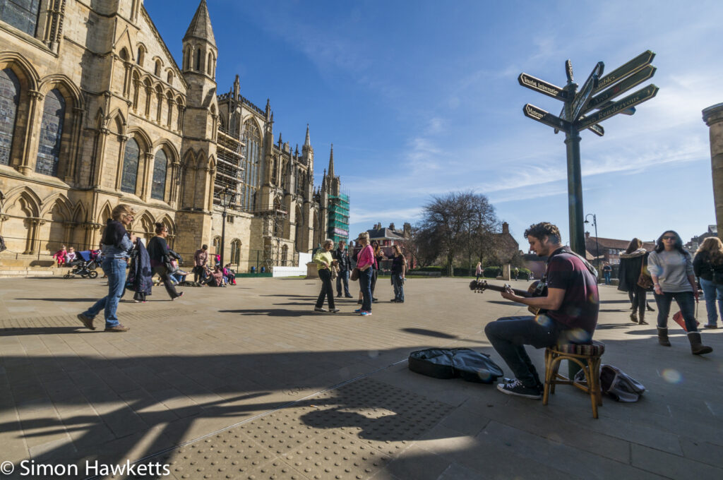 A busker performs in the square outside York Minster