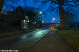 Bus stop in the early morning with the street lights reflecting off the wet road