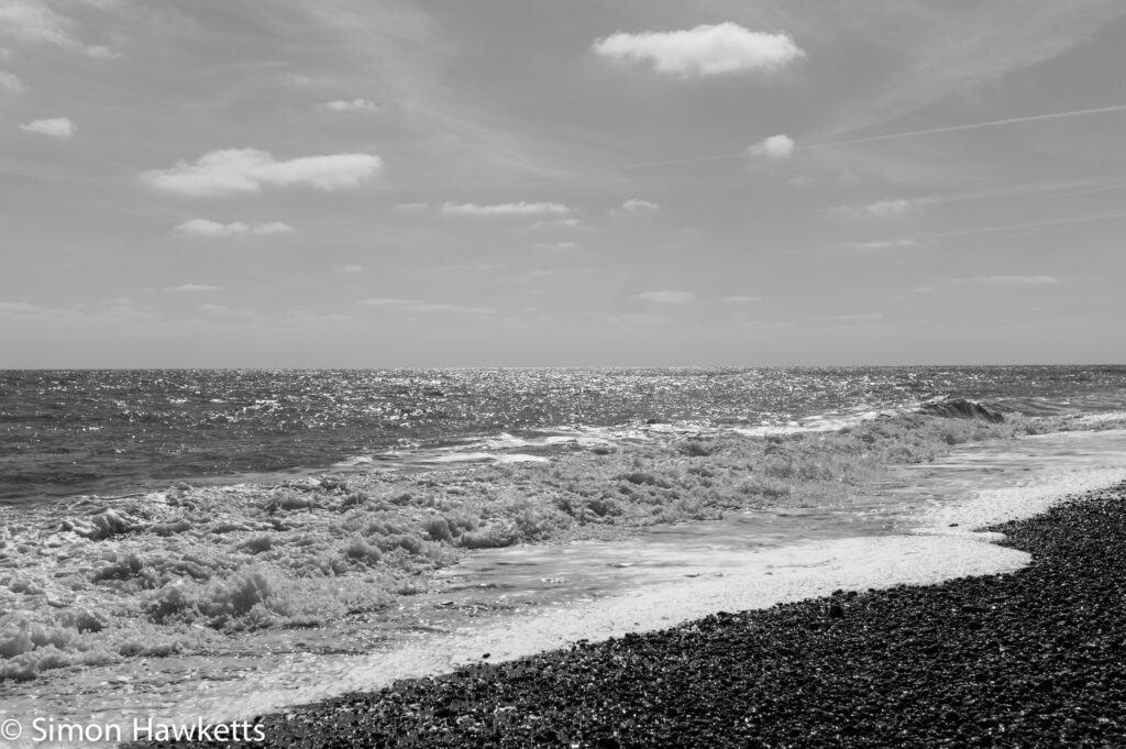 Dunwich Heath Suffolk pictures - Waves breaking over the pebbles in black & white