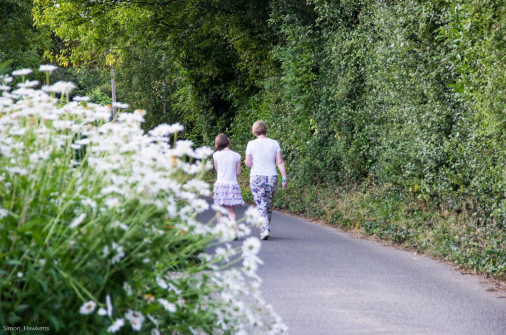 A woman and small girl walking along a country lane